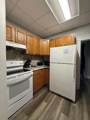 A kitchen with wooden cabinets, a white refrigerator, a stove, and a microwave.