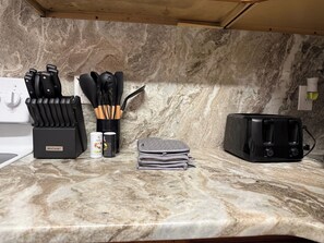 A kitchen with a marble countertop, a McCook® appliance, a toaster, and a set of knives and utensils.