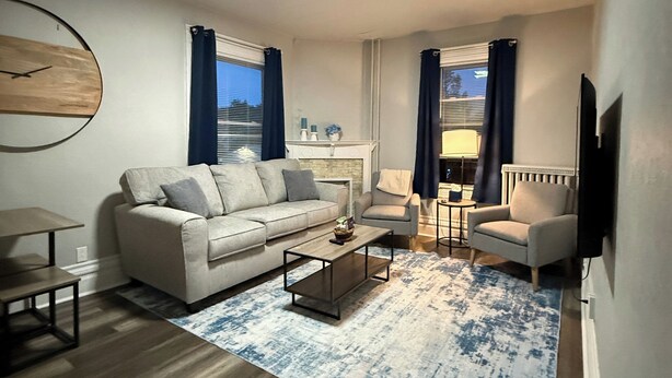 Uma sala de estar moderna com sofá, poltronas, mesa de centro e lareira.