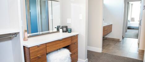 A modern bathroom with a vanity, mirror, and toiletries.