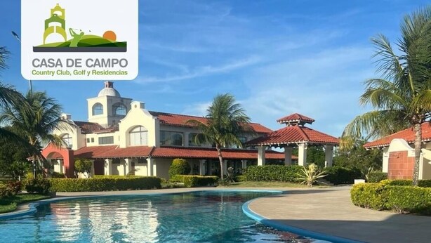A swimming pool with clear blue water, surrounded by palm trees and buildings with red roofs. - 3 Bedroom Apartment- Greenside retreat at golf course. 10 min from the airport. (Santa Cruz de la Sierra)