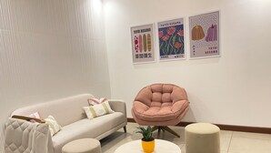 A modern living room with a sofa, a round chair, and two ottomans. There are three framed artworks on the wall. - 3 Bedroom Apartment- Greenside retreat at golf course. 10 min from the airport. (Santa Cruz de la Sierra)