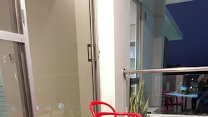 Two red chairs on a balcony with a glass door and a view of a building. - 3 Bedroom Apartment- Greenside retreat at golf course. 10 min from the airport. (Santa Cruz de la Sierra)