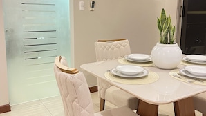 A dining area with a round table, cushioned chairs, a potted plant, and a modern air conditioning unit. - 3 Bedroom Apartment- Greenside retreat at golf course. 10 min from the airport. (Santa Cruz de la Sierra)