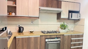 A modern kitchen with wooden cabinets, stainless steel appliances, and a gas stove. - 3 Bedroom Apartment- Greenside retreat at golf course. 10 min from the airport. (Santa Cruz de la Sierra)