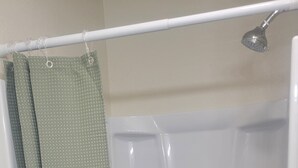 A shower with a green shower curtain and a white bathtub.
