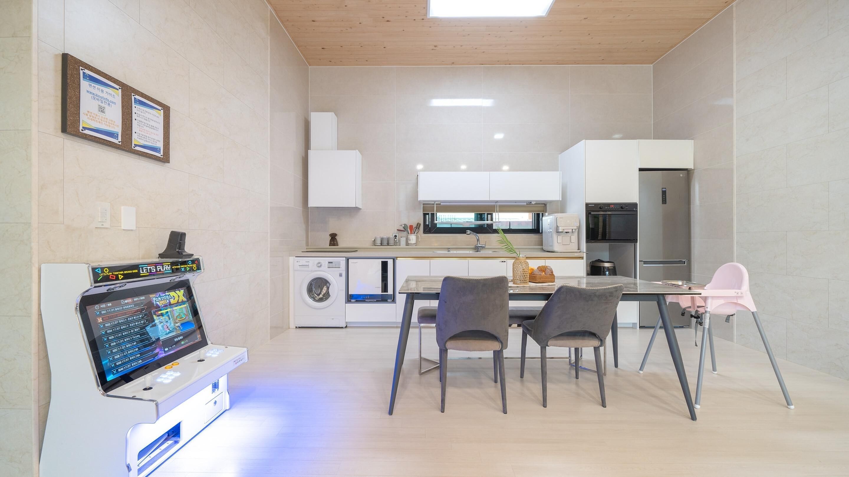 Una cocina moderna con lavadora, una mesa de comedor con sillas y un refrigerador.