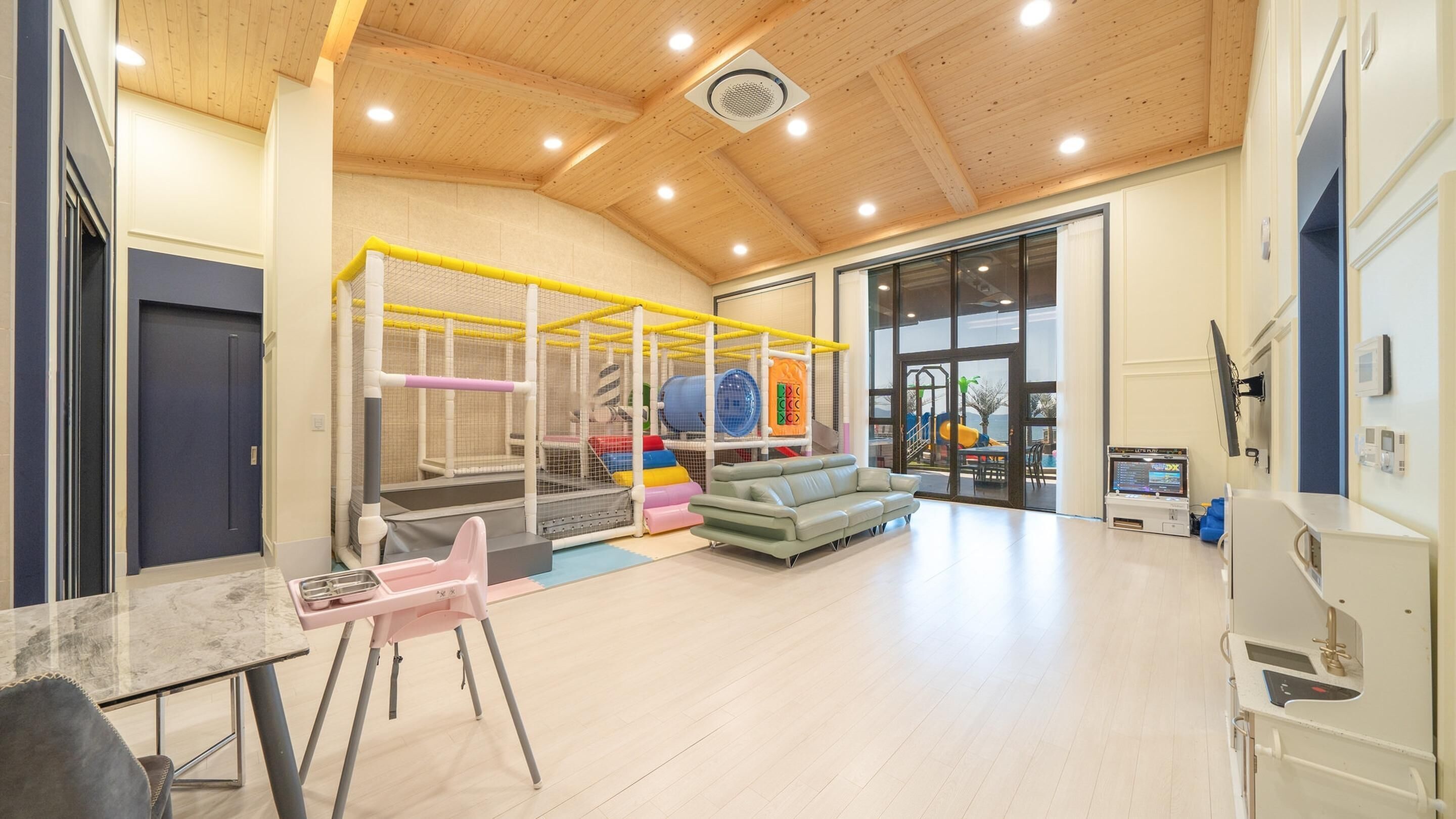 A spacious indoor area with a play area, a sofa, a table, and a kitchenette.