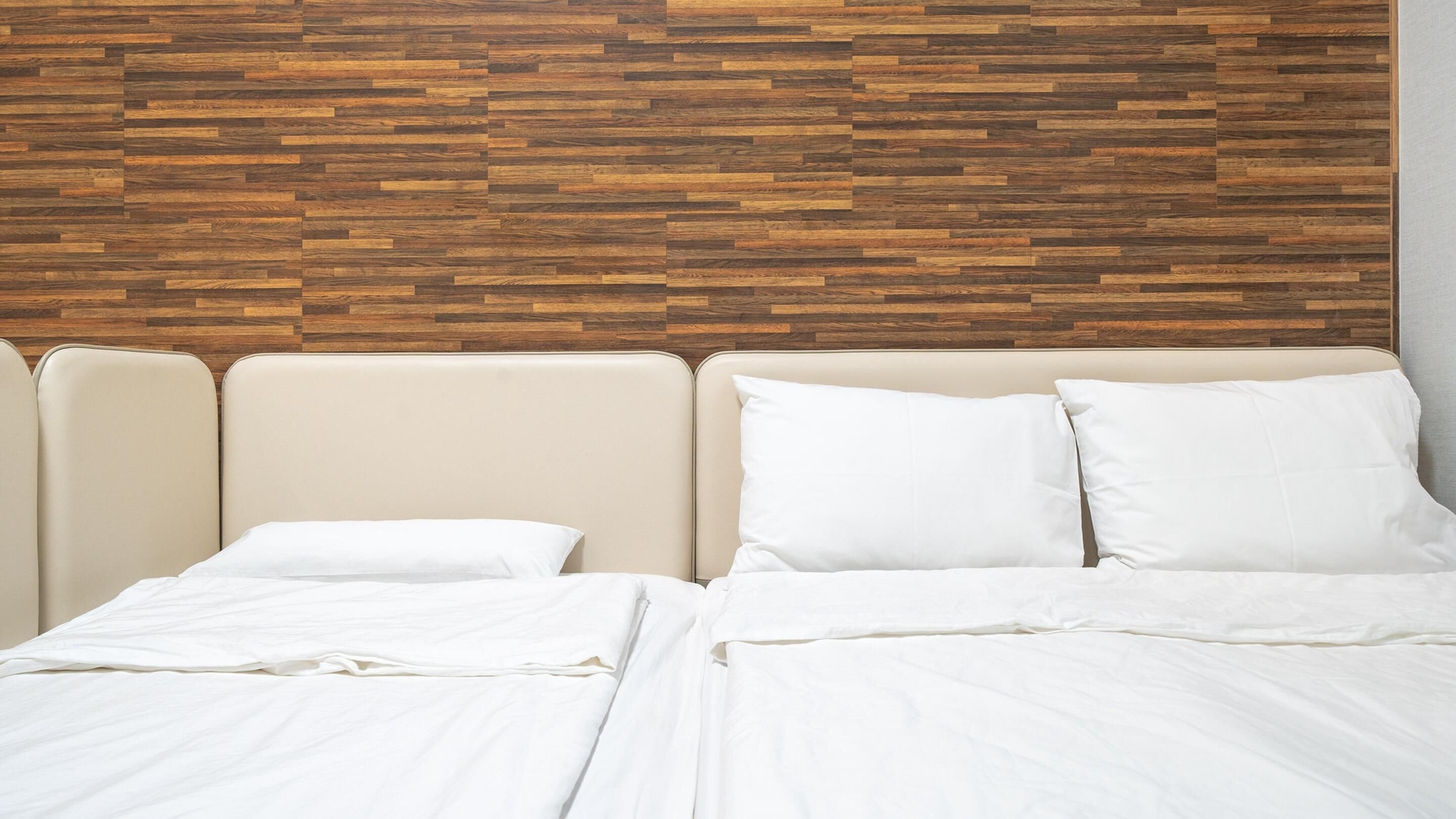 A bed with white linens and a headboard with a wooden panel design.
