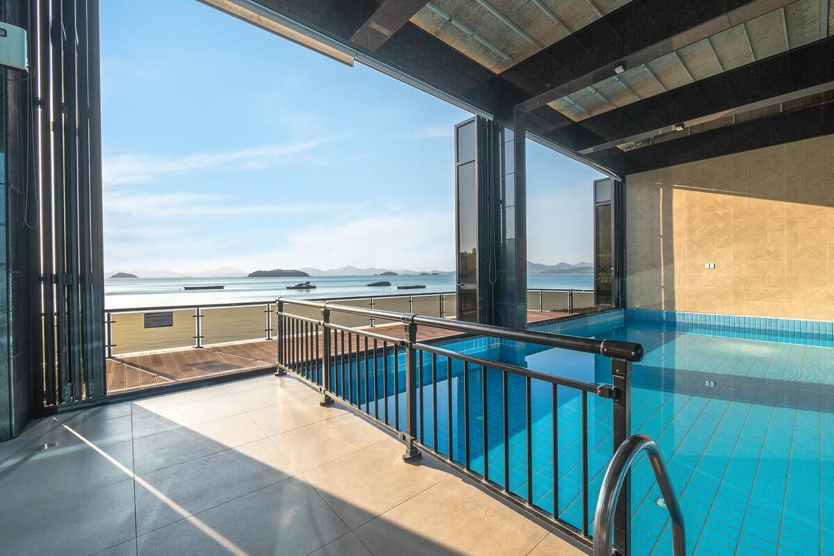A modern indoor swimming pool with a clear view of the sea and distant islands.