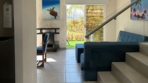 Una cocina moderna con un refrigerador LG empotrado, un comedor con una silla azul y una escalera que lleva a una sala de estar con un sofá azul.