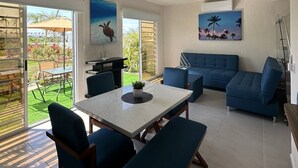 Una sala de estar moderna con comedor, un conjunto de sofás y un ventanal con vista a un jardín.