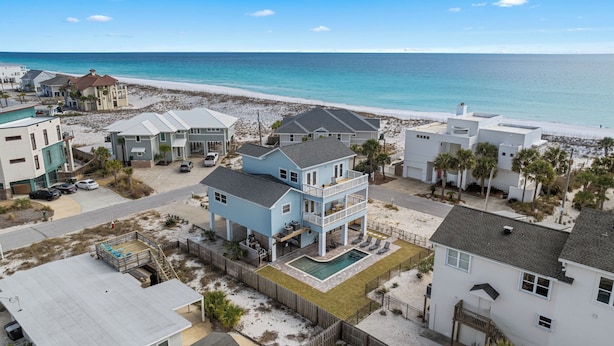 Une propriété située en bord de mer, comprenant une maison à deux étages dotée d’un balcon, d’une piscine et offrant une vue sur la plage.