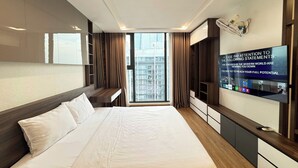A modern hotel room with a large bed, built-in wardrobe, and a television displaying motivational content. - Royal Condotel in Vinhomes Metropolis (Hanoi)