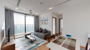A modern living room with a sofa, coffee table, and a dining area with a table and chairs. - Royal Condotel in Vinhomes Metropolis (Hanoi)