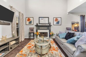 A living room with a fireplace, a sofa, a coffee table, and artwork on the wall.