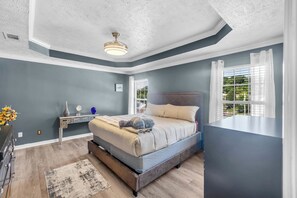 A bedroom with a bed, bedside table, and a window with curtains.