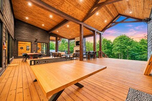 Une terrasse en bois avec des sièges extérieurs et une vue sur les arbres.