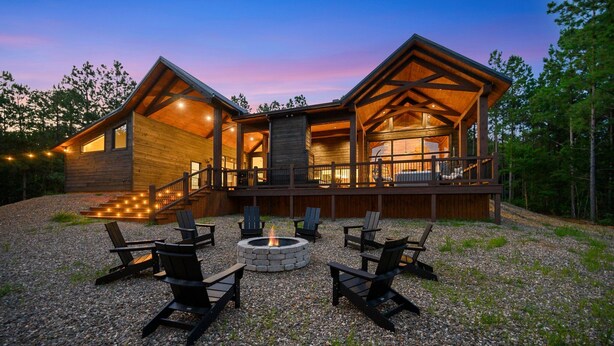 Une cabane en rondins avec une terrasse, un espace salon extérieur et un foyer.