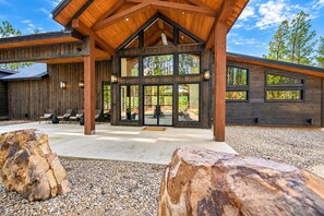 A modern building with a wooden exterior, large windows, and a covered entrance area with seating. - Spacious Luxe 4BR | Game Room | Fire Pit & Hot Tub (Broken Bow)