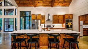 Une cuisine moderne dotée d’un grand îlot central, de meubles en bois et d’appareils électroménagers en acier inoxydable.