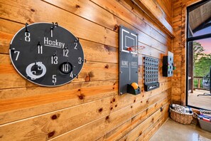 A wooden wall with a clock, a basketball hoop, and a guest keycard holder. - Spacious Luxe 4BR | Game Room | Fire Pit & Hot Tub (Broken Bow)