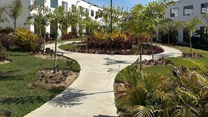 A modern building with a pathway surrounded by landscaped gardens and palm trees. - Puerto Vallarta Altavela Egina 62 (Valle de Banderas)