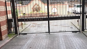 Una entrada protegida por un muro de ladrillo y un camino pavimentado que conduce a un estacionamiento.