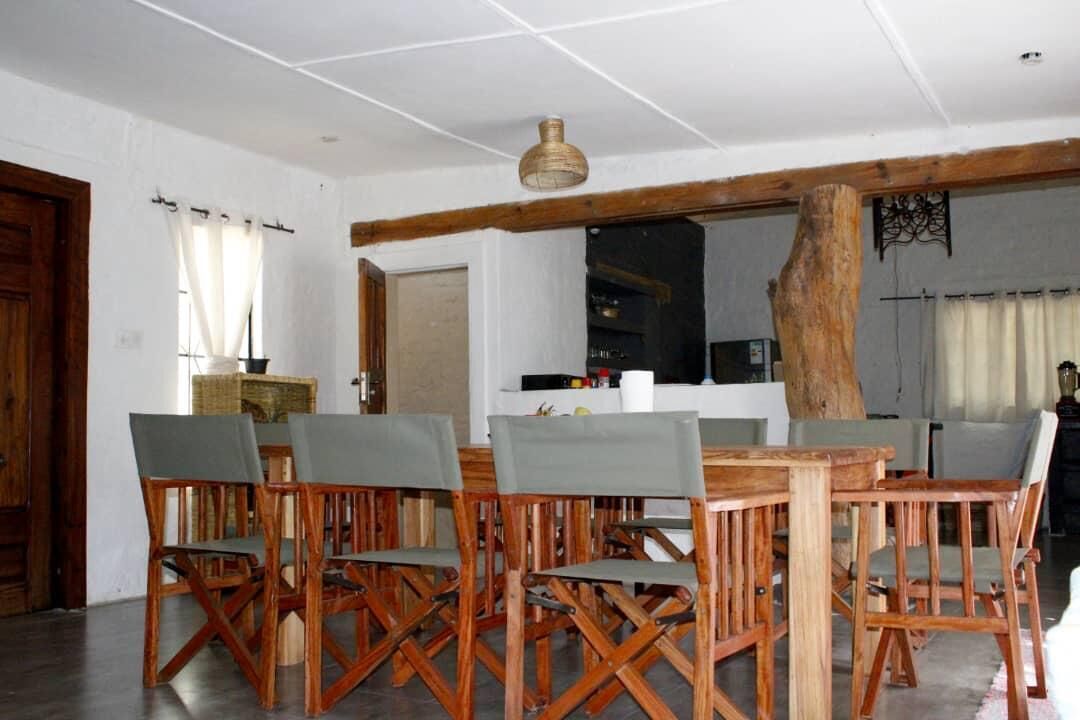 Ein Essbereich mit Holztisch und -stühlen, einer hängenden Leuchte und einem großen Baumstamm im Hintergrund.