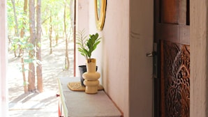 Une porte en bois ornée de sculptures complexes, une petite table sur laquelle est posée une plante en pot et un miroir accroché au mur.