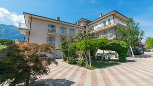 Een meerlaags hotel met balkons, een geplaveid binnenterrein en weelderige begroeiing.