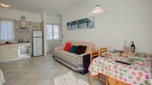 Een compacte keuken met een eethoek, een bank en een schilderij aan de muur.