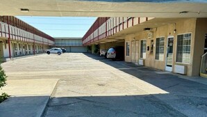 A parking lot with a building entrance, marked by a sign indicating an 8 ft clearance and an entrance arrow. - Regency Inn Fresno (Fresno)