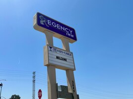 Un cartel que dice 'EGENCY INN', con el mensaje 'BIENVENIDOS' y el símbolo de 'HBO-CABLE'.