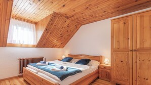 A wooden-framed bedroom with a sloped ceiling, a large wardrobe, and a radiator. - Organic Homestead Mikl Spruce Tree Apt, Slovenj Gradec, Slovenia (Slovenj Gradec)