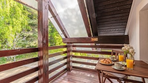 A wooden deck with a table set for breakfast, including croissants, juice, and a vase of flowers. - Organic Homestead Mikl Spruce Tree Apt, Slovenj Gradec, Slovenia (Slovenj Gradec)