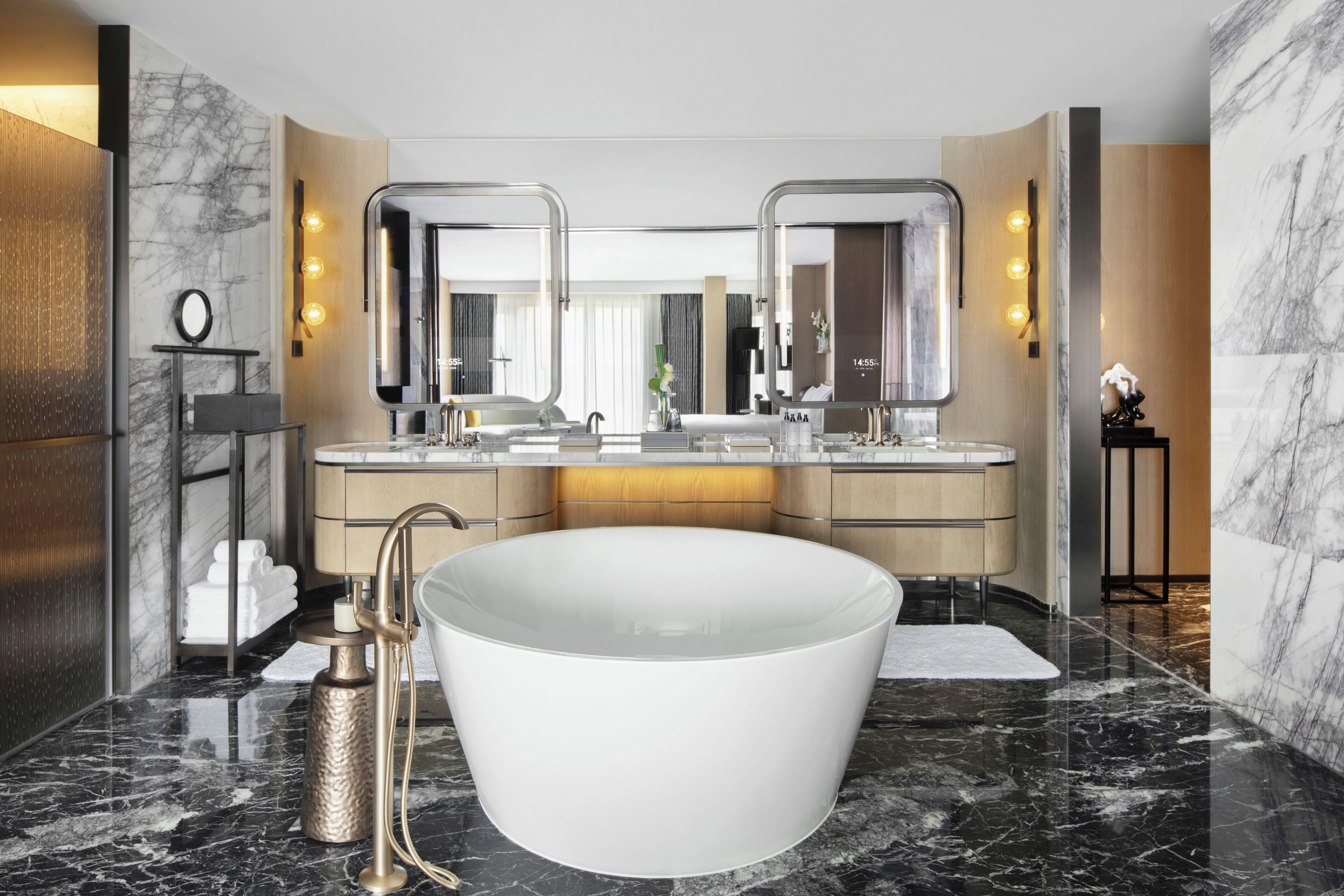 A modern bathroom with a large freestanding bathtub, dual sinks, and a vanity with a mirror.