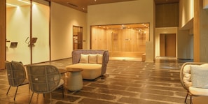 A lobby with a reception desk, seating area with chairs and a sofa, a wooden reception desk, and a wall with a wooden panel.