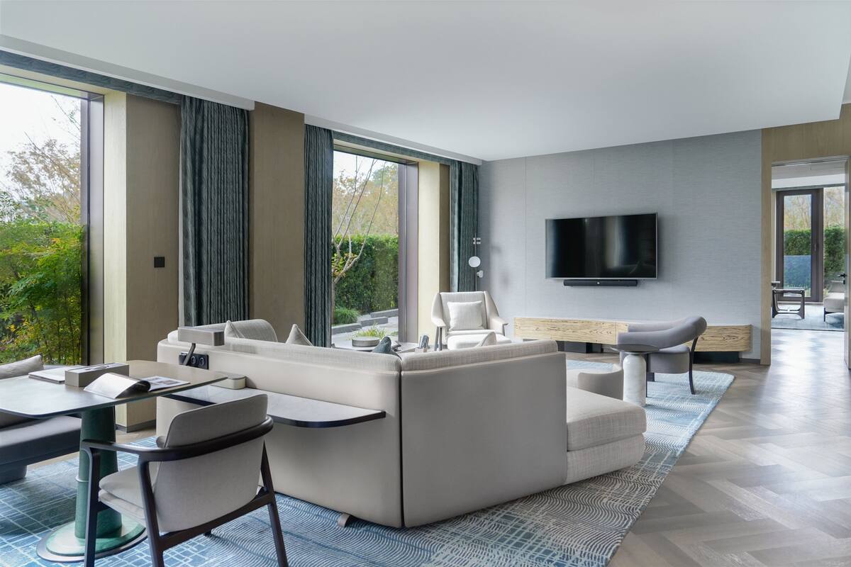 A modern living room with a sofa, chairs, a TV, and a dining area.