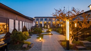 A modern building with a central courtyard, surrounded by trees and illuminated by ground lights. - Intercontinental Xiangyang by IHG (Xiangyang)