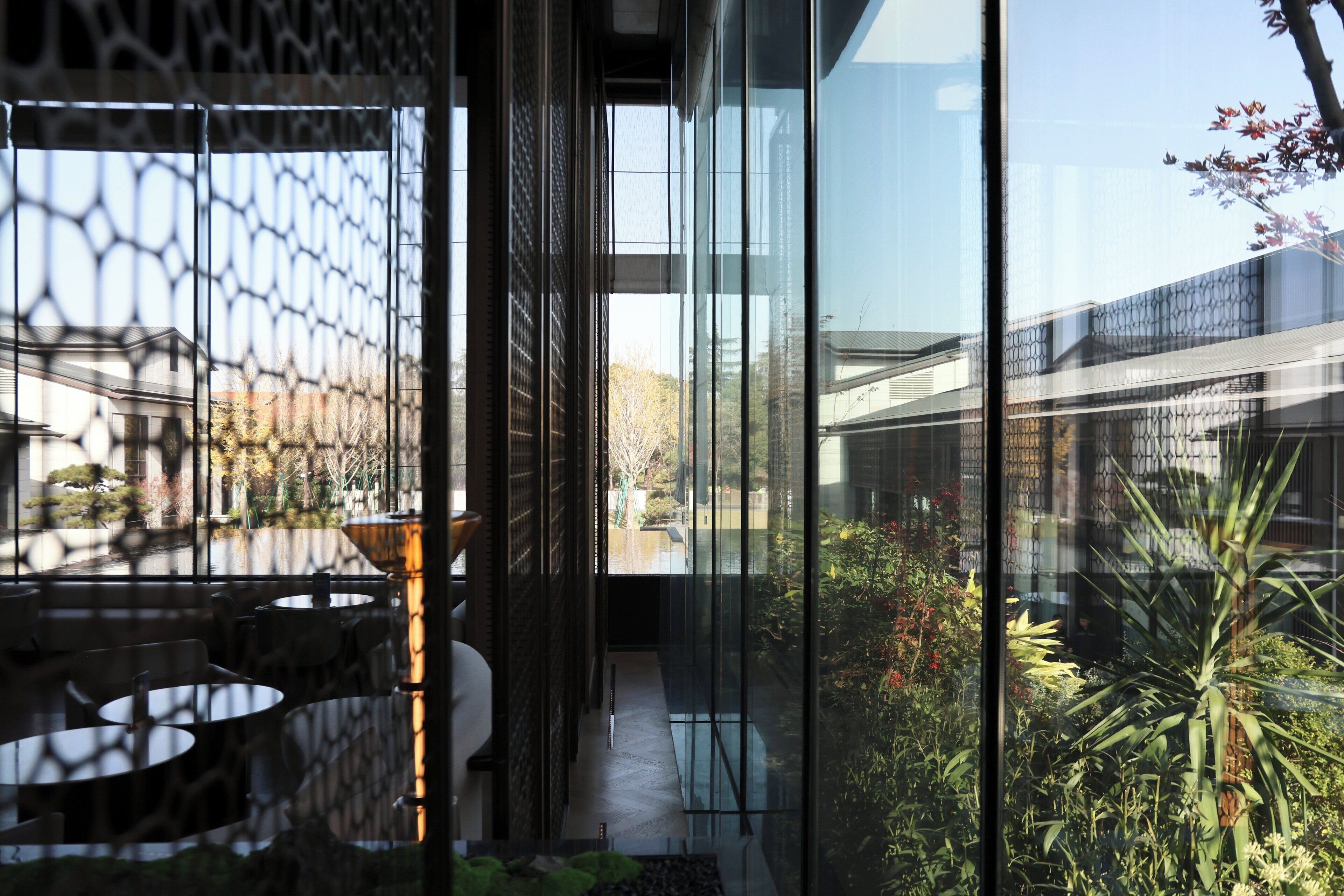 A modern interior with a glass partition, a staircase, and a view of the outside.