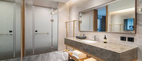 A modern bathroom with a glass shower enclosure, a marble vanity with a sink, and a large mirror.