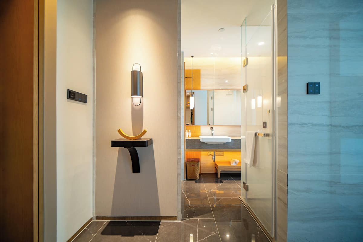 Een moderne badkamer met een douchecabine van glas, een wastafelmeubel en een wandlamp.