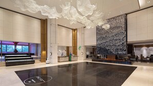 A spacious lobby with a reception desk, seating area, and a large decorative wall. - Holiday Inn Ningbo Xianshan Damu Bay by IHG (Ningbo)