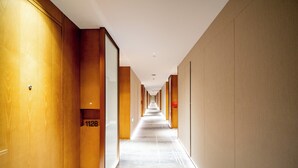 A long, narrow hotel corridor with wooden walls and a carpeted floor. - Holiday Inn Ningbo Xianshan Damu Bay by IHG (Ningbo)