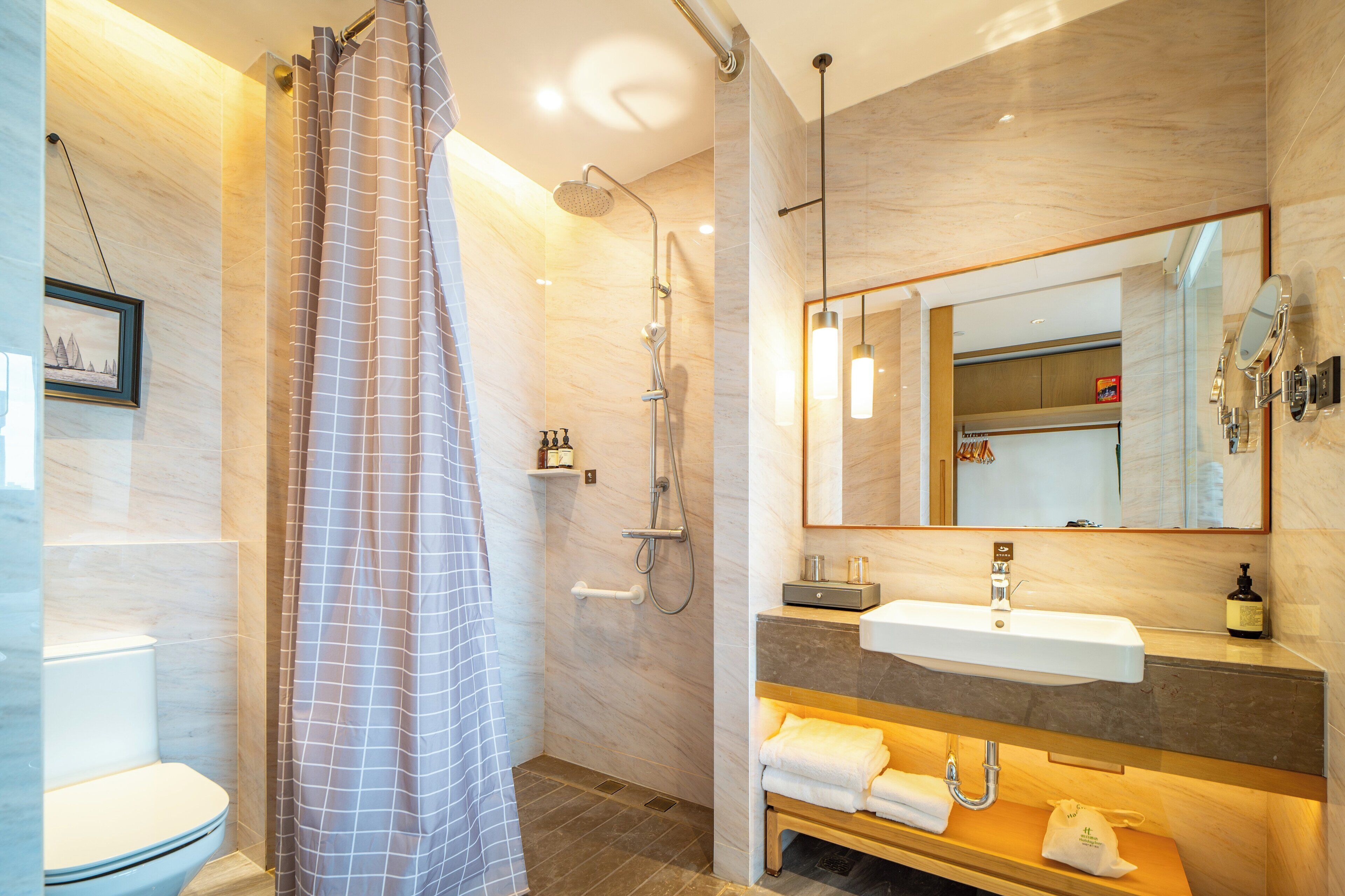 A modern bathroom with a shower, toilet, and vanity.