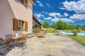 A patio with outdoor seating, a swimming pool, and a building with large windows. - Grad Inn Boutique Villa Suite Bay Leaf, Gračišče, Slovenia (Gračišče)
