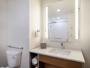 A modern bathroom with a toilet, sink, and mirror. - EVEN Hotel Miami - Doral Area, by IHG (Miami)