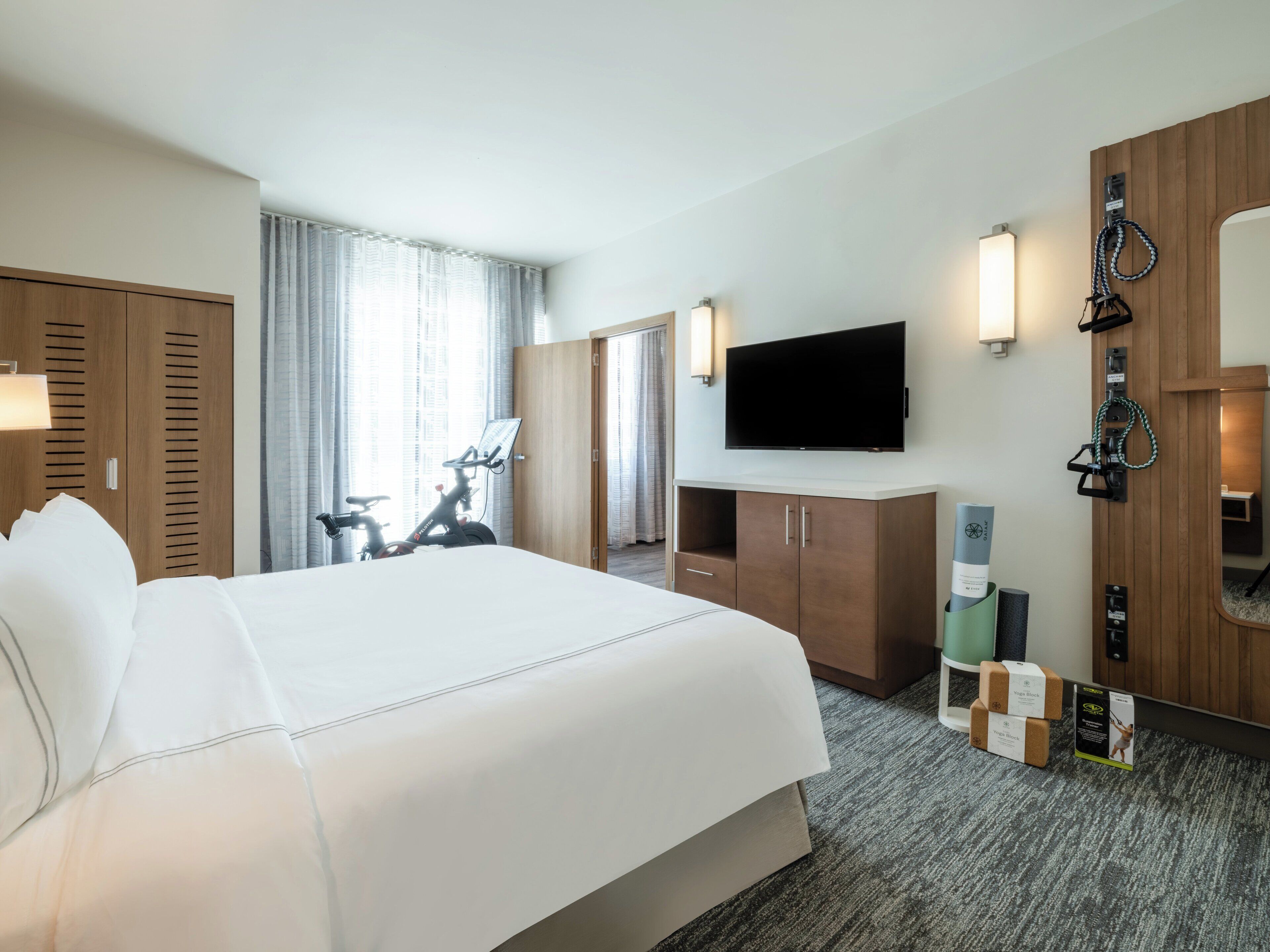 Une chambre d’hôtel avec un grand lit, une télévision, un bureau et un vélo.