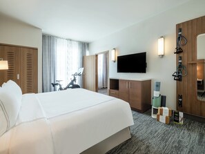 A hotel room with a large bed, a TV, a desk, and a bicycle. - EVEN Hotel Miami - Doral Area, by IHG (Miami)